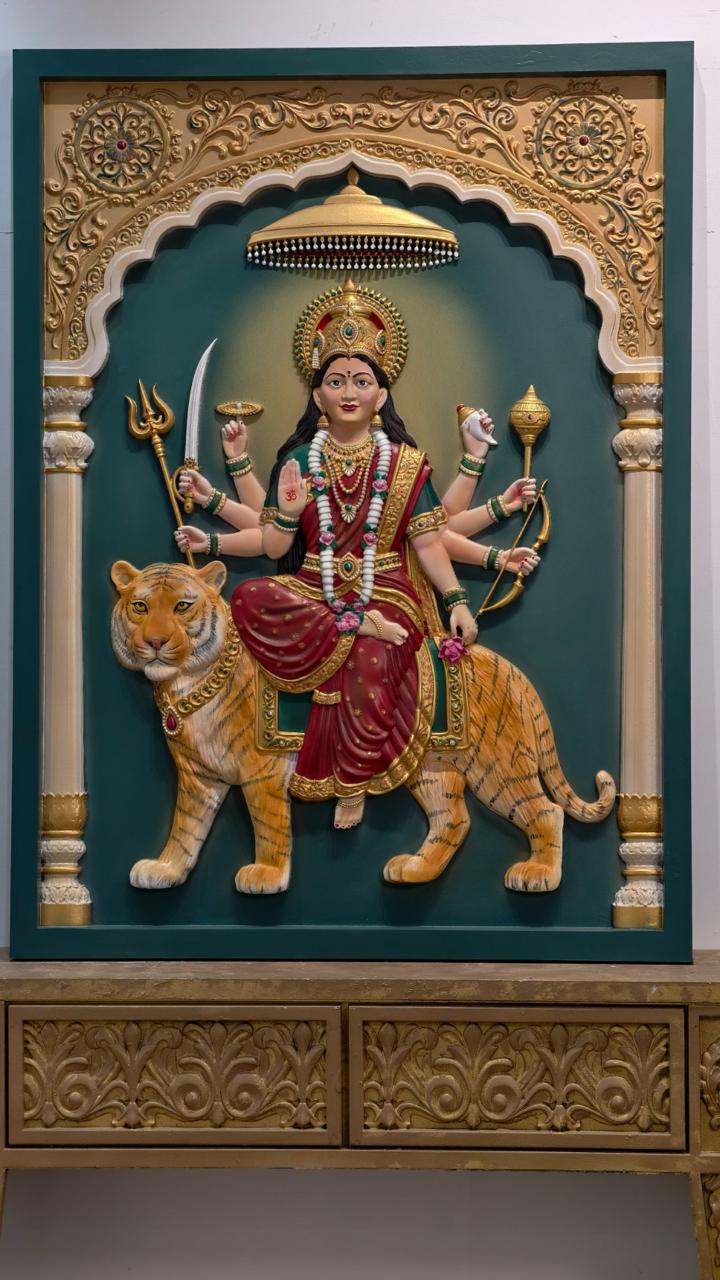 Painted relief of Durga seated on a tiger beneath a carved arch