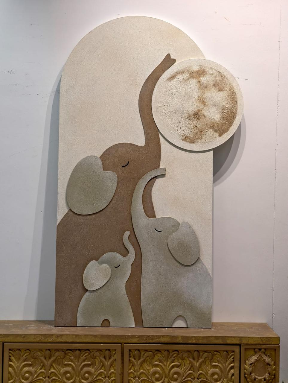 Textured relief of an elephant family beneath a full moon