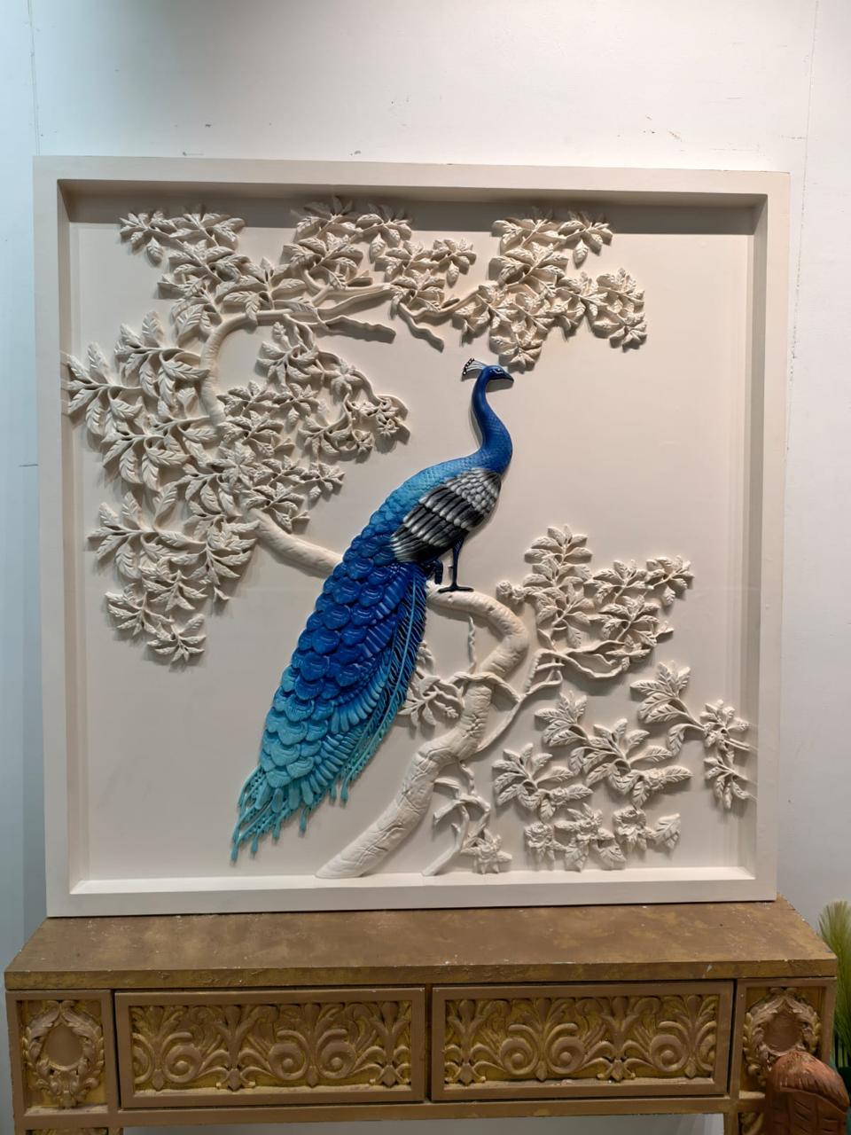 Blue peacock perched on a white carved flowering branch