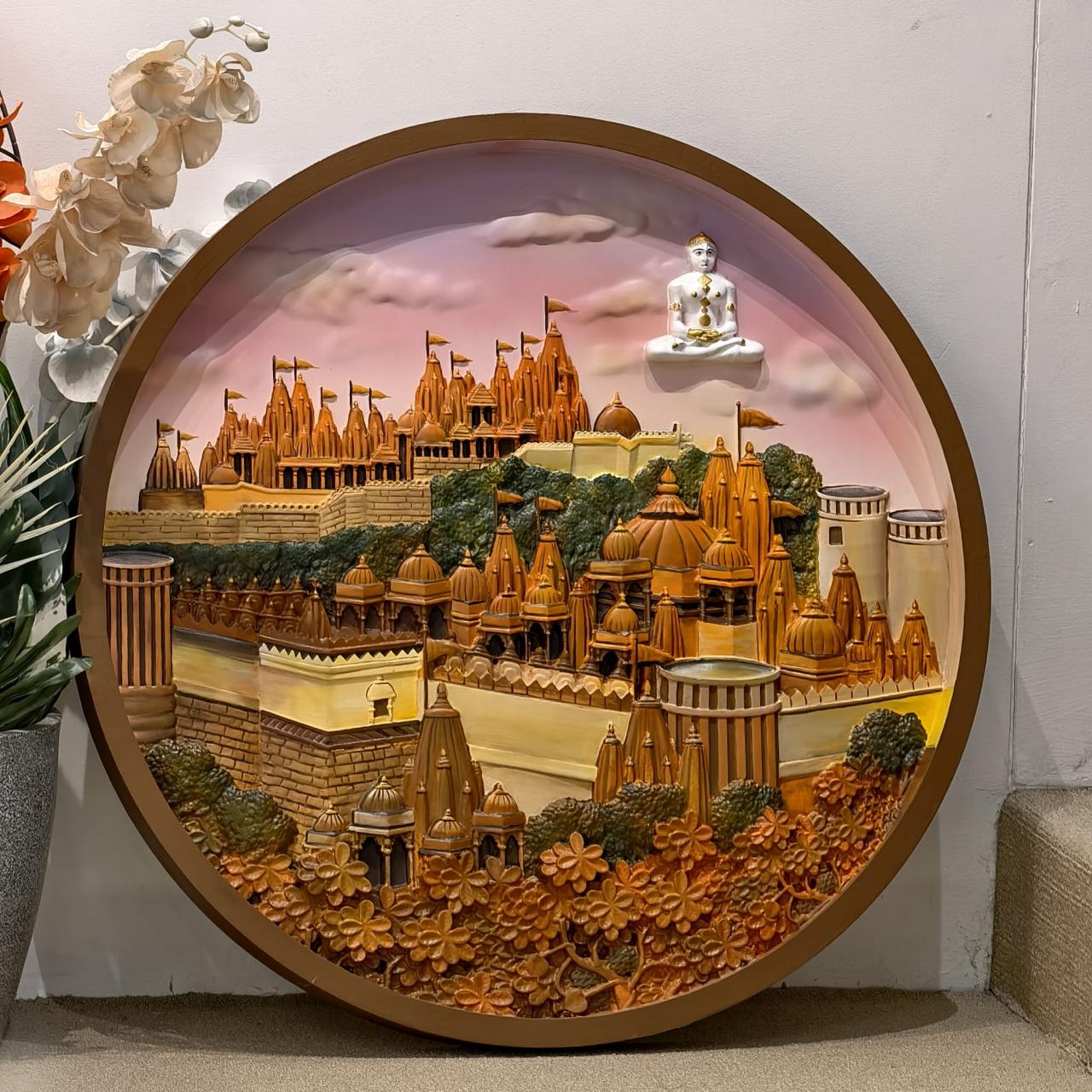 Round painted relief of the Shatrunjay temple complex under a pink sky