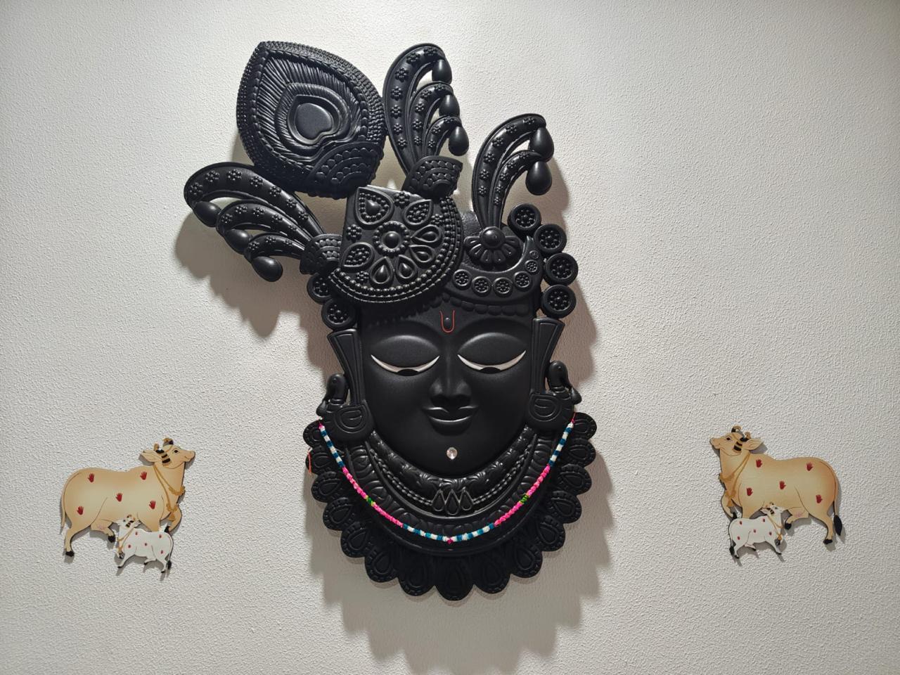 Black Shrinathji face relief with a feathered crown and beaded necklace