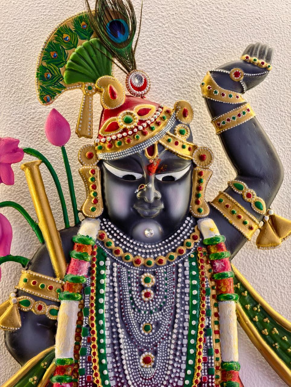 Close-up of a hand-painted Shrinathji relief with beaded jewellery and a peacock-feather crown